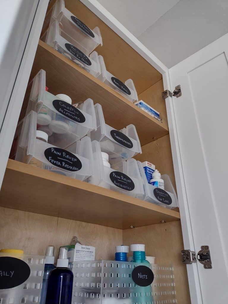 close up of top portion of bathroom cabinet and containers that are labeled and organized